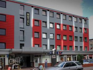a red and white building with a car in front of it at Hotel Pojezierze in Szczecinek