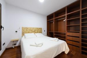 a bedroom with a large white bed with wooden cabinets at BAJAMAR - renovated apart. nex to the sea in Arucas