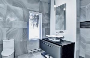 Un baño con lavabo, inodoro y ventana. en Chalet 06 Chemin Blanc by Les Chalets Alpins, en Stoneham 43 fotos más