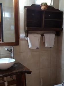 a bathroom with a sink and a mirror and towels at Finca Las Pircas Casa de Adobe in Famatina