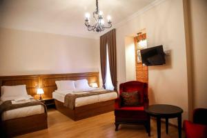 a bedroom with two beds and a chair and a chandelier at B&B rooms in Tbilisi City
