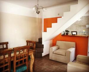 a living room with a table and a chair and stairs at Altos del Tala Deptos - Cabañas in Embalse