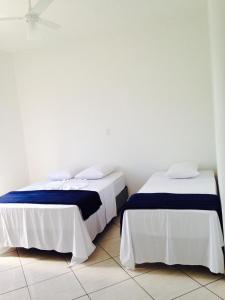 dos camas sentadas una al lado de la otra en una habitación en Pousada Manacá, en São José do Rio Pardo