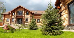 a log cabin with two pine trees in front of it at Банний клуб Столичний in Vita-Pochtovaya