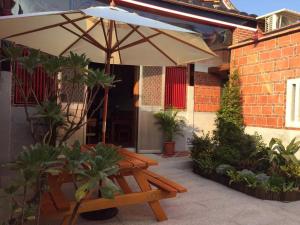 - une table de pique-nique en bois avec un parasol sur la terrasse dans l'établissement 八八古藝民宿, à Jinning