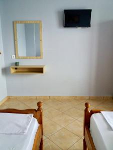 a room with two beds and a mirror and a tv at Ionian Bay Rooms in Qeparo