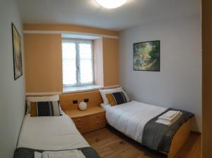 2 łóżka w małym pokoju z oknem w obiekcie Casa Zone w mieście Tesero