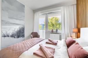 sypialnia z łóżkiem z różowymi poduszkami i oknem w obiekcie Blue Mare Bliżej Morza w Kołobrzegu