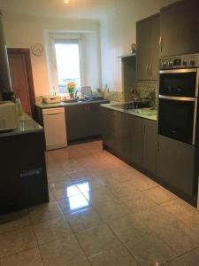 a kitchen with gray cabinets and a tile floor at Heddfan in Carmarthen