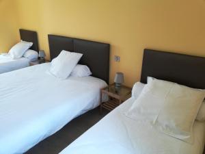 1 dormitorio con 2 camas con sábanas y almohadas blancas en Hôtel de la Poste Chez Cécile, en La Grande-Verrière