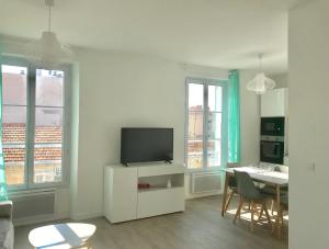 a living room with a tv and a table with chairs at Cannes la bocca appartement in Cannes