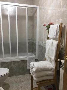 ein Badezimmer mit einer Dusche und einem Stuhl mit Handtüchern in der Unterkunft Vergarillas 1 in Avila