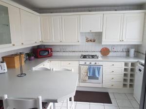 a kitchen with white cabinets and a table and a microwave at 3 bed room house in Aberdeen
