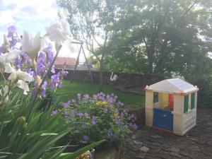 una casa de juguete en un jardín con flores en Gîte L'Instant Durable, en Oberbronn