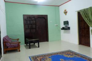 a room with a door and a chair and a rug at Homestay Tok Abah Kuala Rompin 1 Bilik Tidur in Kuala Rompin
