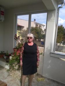kobieta w czarnej sukience stojąca przed oknem w obiekcie Apartment Tičić w mieście Povljana