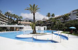a swimming pool with a palm tree in the middle at Penthouse DELUXE, Carolina Park, Marbella in Marbella
