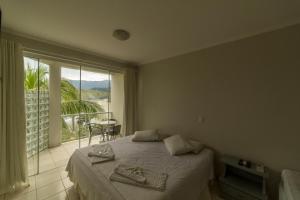 una camera da letto con un letto e una grande finestra di Panoramica Residencial a Barequeçaba Altre 37 foto