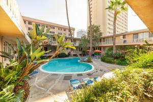 a swimming pool in a courtyard with chairs and buildings at Cal Mar Hotel Suites in Los Angeles