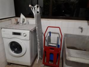 a washing machine and a red cart next to a washer at Casa da Aldeia in Terras de Bouro