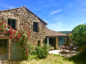 une maison en pierre avec une table, des chaises et des fleurs dans l'établissement La Magnanerie d'Audabiac, à Lussan