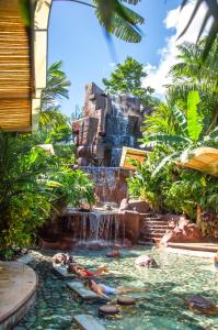 uma cascata num resort com pessoas deitadas numa piscina em Baldi Hot Springs Hotel & Spa em Fortuna