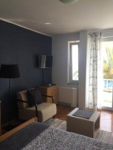 a bedroom with a bed and a chair and a window at Guesthouse Punta Mira - Beachfront in Novalja