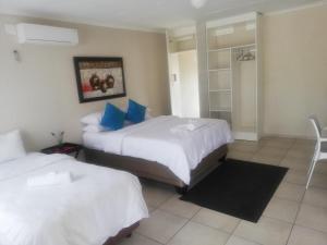 a hotel room with two beds with blue pillows at BTV Guesthouse in Hazyview