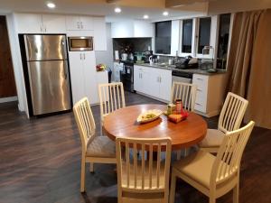 Il comprend une cuisine avec une table et des chaises en bois ainsi qu'une cuisine équipée d'un réfrigérateur. dans l'établissement City Gardens Suites B&B, à North Vancouver