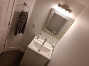 a white bathroom with a sink and a mirror at City Gardens Suites B&B in North Vancouver