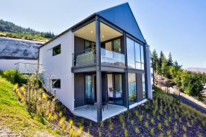 a house on a hill with glass walls at Peak View Residence in Queenstown