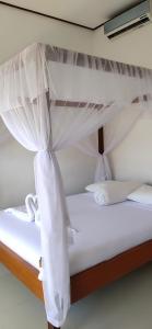 a white bed with white curtains on it at Warung Jemeluk & Home Stay in Amed