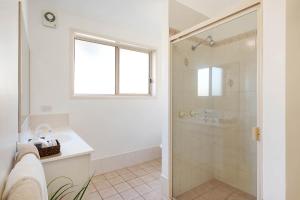 a bathroom with a shower, sink, and toilet at Black Dolphin Motel & Apartments in Merimbula