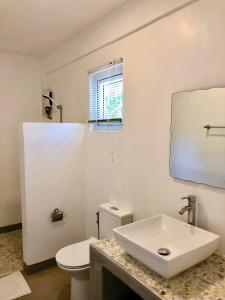 La salle de bains blanche est pourvue d'un lavabo et de toilettes. dans l'établissement Sunset Cove Beach & Dive Resort, à Romblon