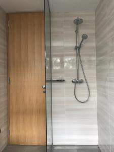 een douche in een badkamer met een houten deur bij Klinar - Cosy apartment with a terrace in Bled