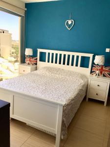 sypialnia z białym łóżkiem i niebieską ścianą w obiekcie Paradise Apartment w mieście Protaras