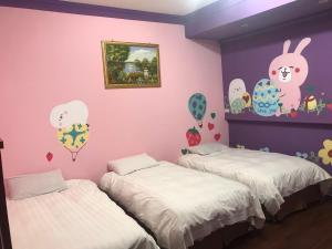 2 camas en una habitación con una pared de color rosa en 陽光綠堤民宿 en Taitung