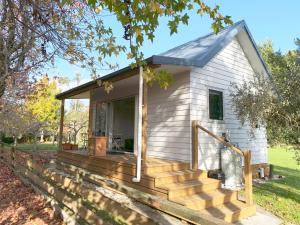 a tiny house with a porch and a deck at Mirror Creek Holiday Cottage in Ruatapu