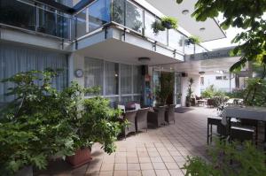 um pátio exterior com mesas, cadeiras e plantas em Hotel Rondinella em Cesenatico