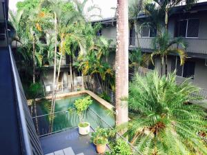 an apartment balcony with palm trees and a swimming pool at Lake Central Cairns in Cairns