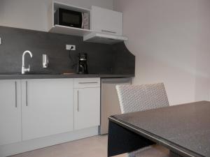 a kitchen with white cabinets and a black counter top at Appart-hôtel Chanzy / Angoulême in Angoulême