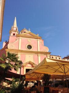 a large pink building with a clock tower at Grand Hôtel De Calvi in Calvi