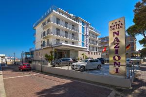 un bâtiment avec des voitures garées dans un parking dans l'établissement Hotel Delle Nazioni, à Caorle