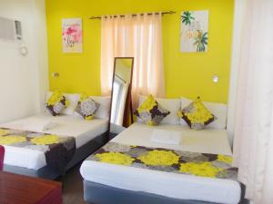 two beds in a room with yellow walls at Abrhys Ridge Inn in Coron