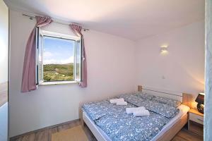 a small bedroom with a bed and a window at Holiday House Rab in Rab