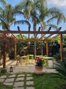 a patio with a wooden pergola and tables and palm trees at Villa Carati in Acireale