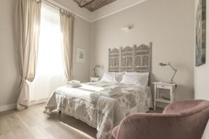 een witte slaapkamer met een bed en een stoel bij Casa di Ele in Rome