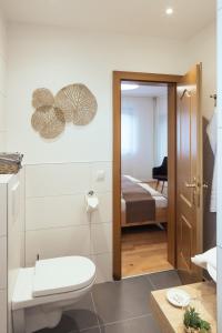 a bathroom with a toilet and a room with a bed at Pension Auszeit Velden in Velden am Wörthersee