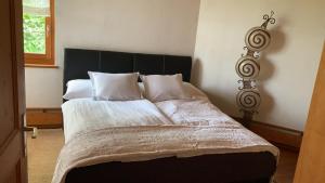 un letto con lenzuola e cuscini bianchi in una camera da letto di Bed & Breakfast Region Murtensee a Münchenwiler