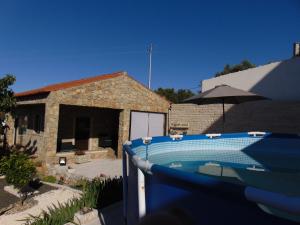 a pool in front of a house with an umbrella at Casa do Canto in Casais dos Monizes